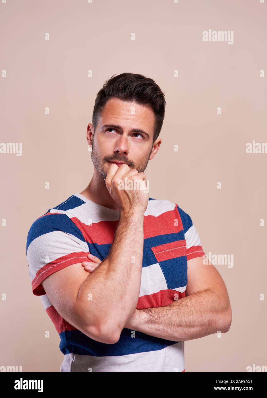 Thoughtful, young man looking up in studio shot Stock Photo