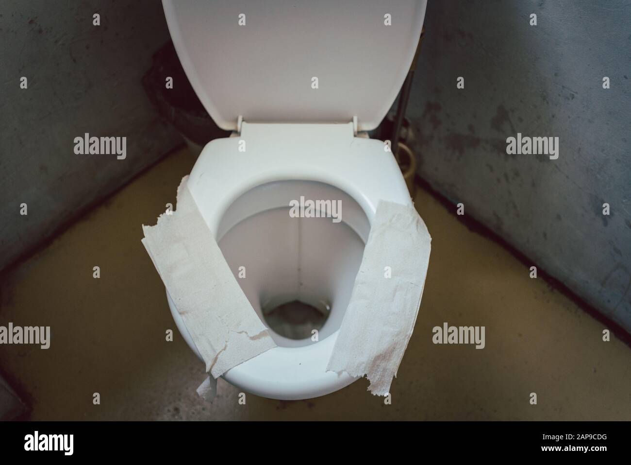 Filthy toilet seat covered with toilet paper as sit down insulation Stock Photo
