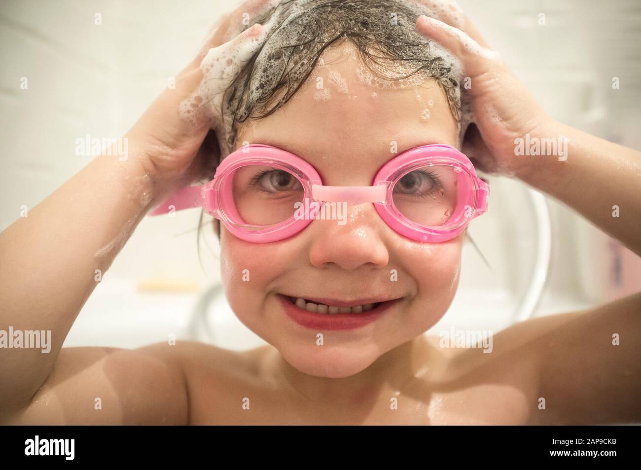 4 years boy wearing goggles at bathtub. No more eyes stinging washing hair concept Stock Photo