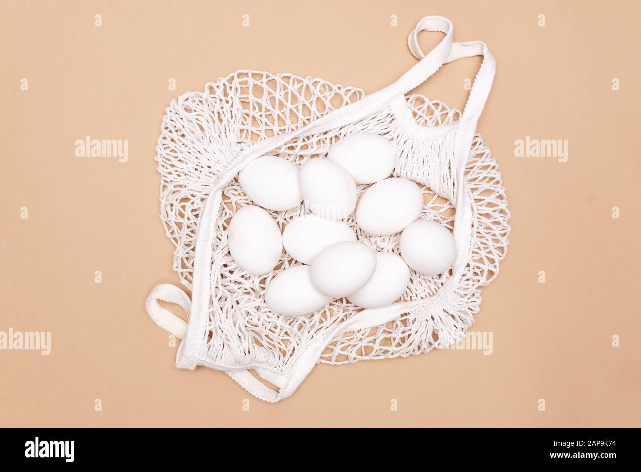 Easter table concept background with string bag, colorful Easter eggs and yellow tablecloth. Stock Photo