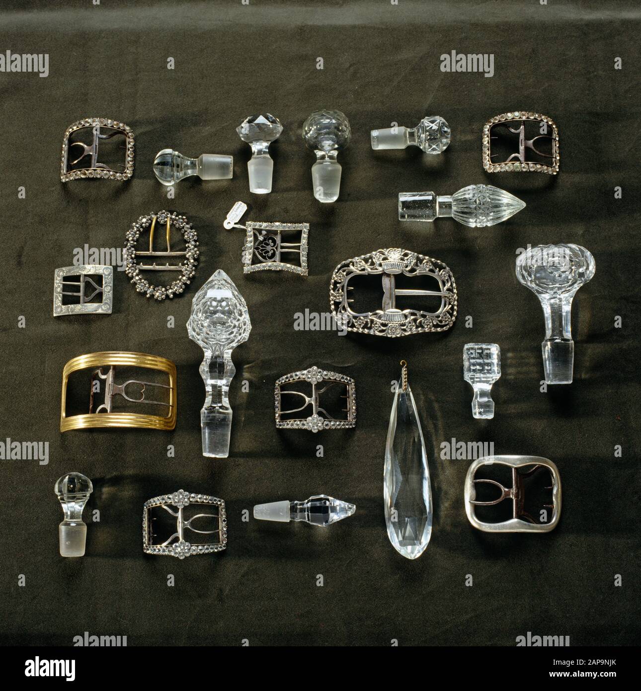 Detail of the P.M. Ward Collection at Llanerchaeron of glass and crystal bottle stoppers, a chandelier drop and silver belt buckles arranged on a dark Stock Photo