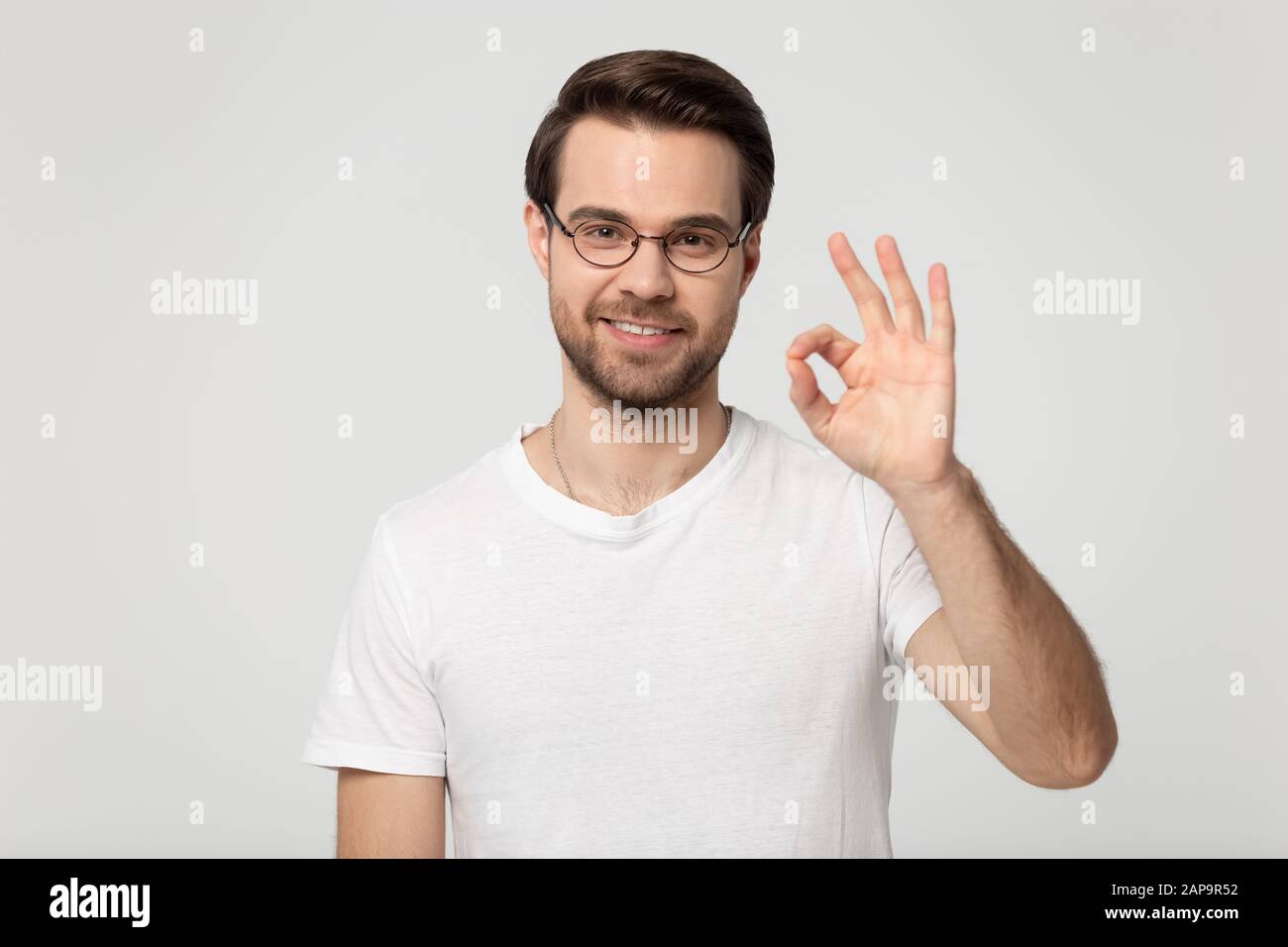 Head shot portrait young happy guy in eyewear showing okay gesture. Stock Photo