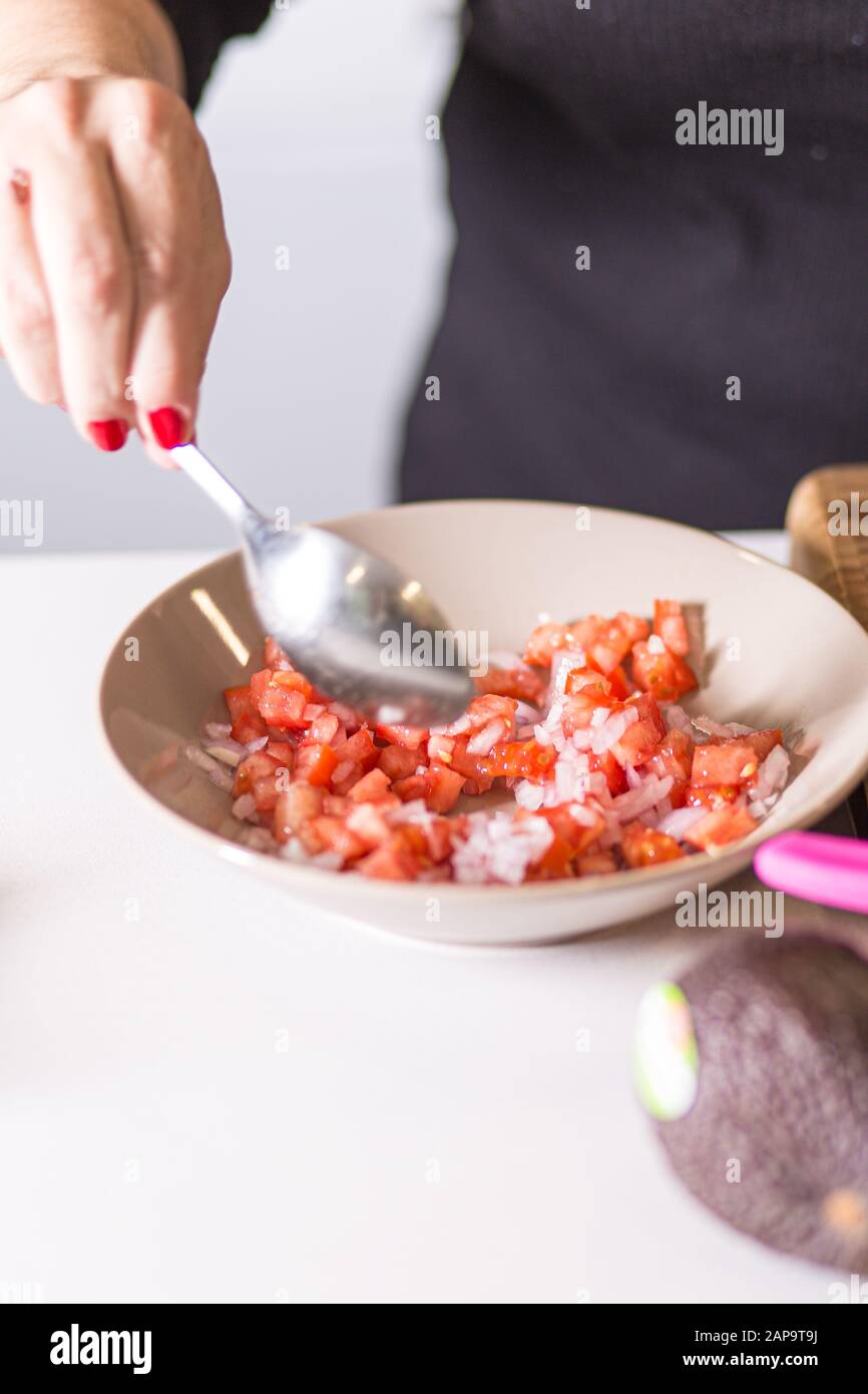 Cutting and preparing tomato and onion on dices for a salad and guacamole ingredients Stock Photo