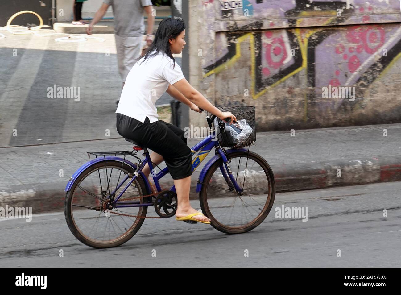 Bangkok, Thailand - December 26, 2019: Woman riding a bicycle on Sukhumvit Soi 4. Stock Photo