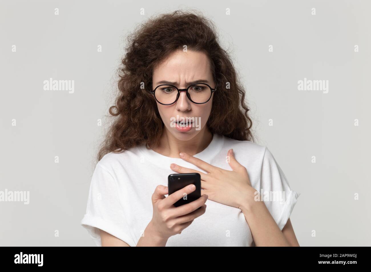 Scared worried millennial woman looking at device screen. Stock Photo