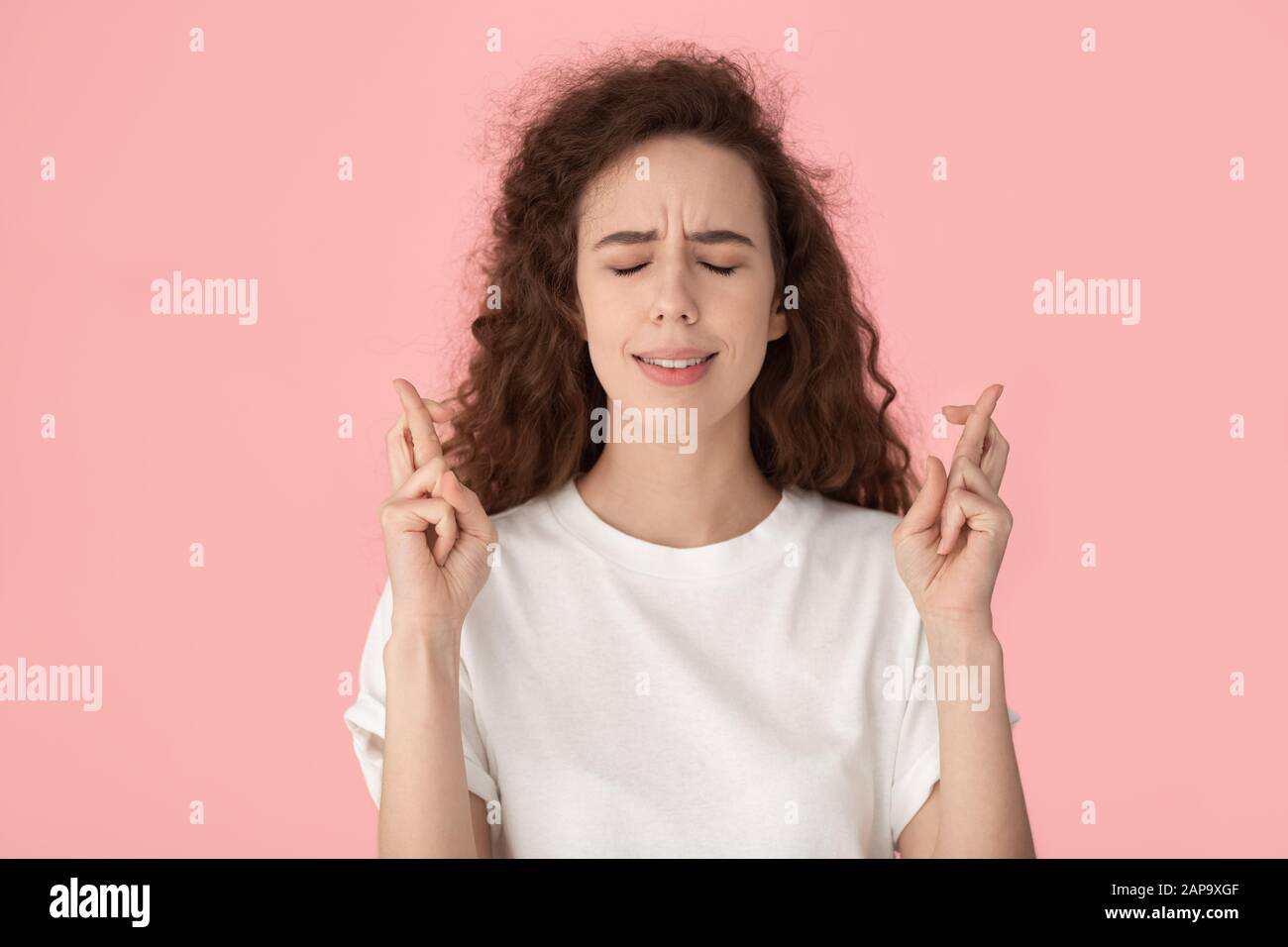 Superstitious girl crossing fingers, hoping for good luck. Stock Photo