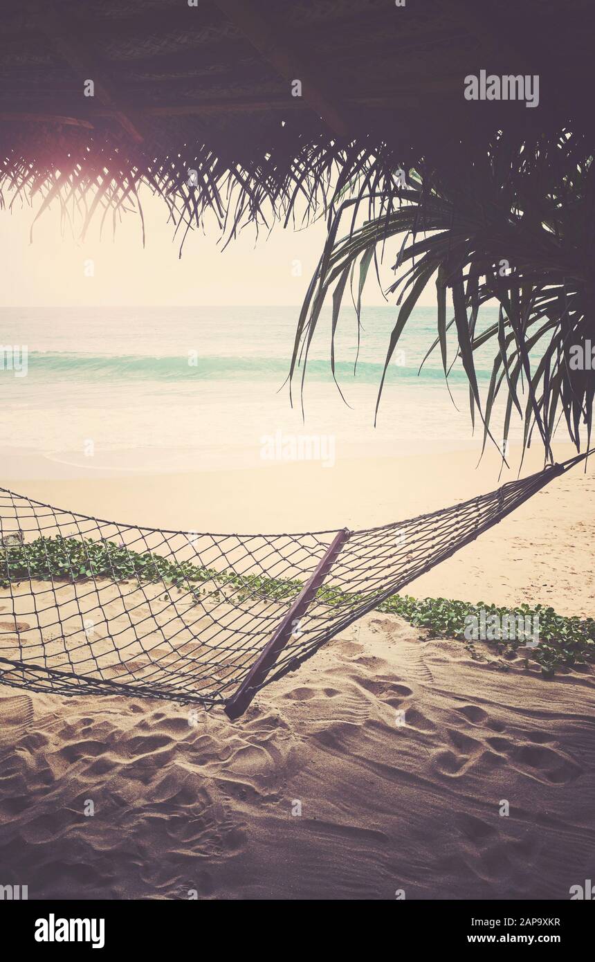 Tropical beach with hammock, summer getaway concept, retro color toning applied. Stock Photo