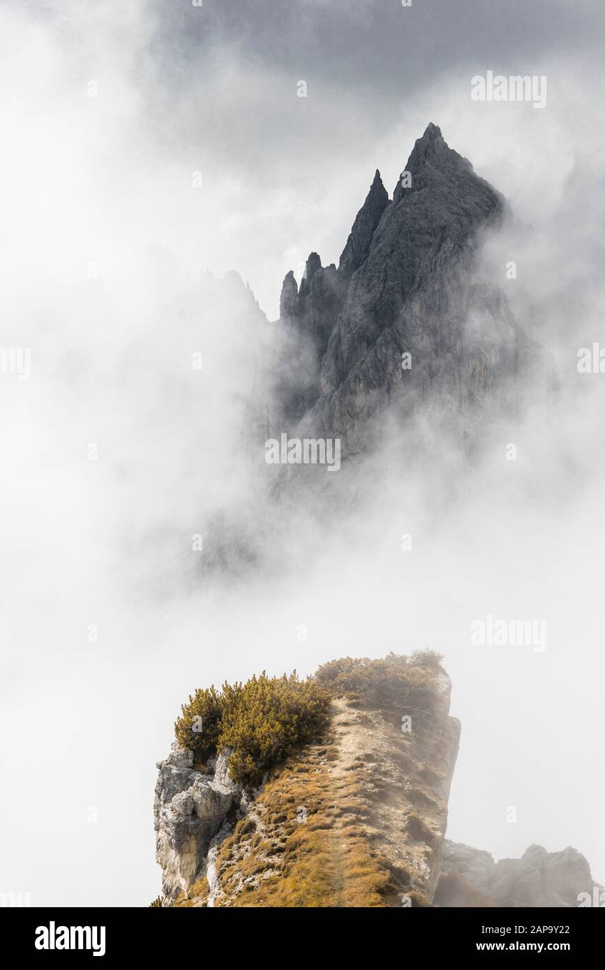 Rocky ledge, ridge, behind mountain peaks and pointed rocks, dramatic clouds, Cimon di Croda Liscia and Cadini Group, Auronzo di Cadore, Belluno Stock Photo