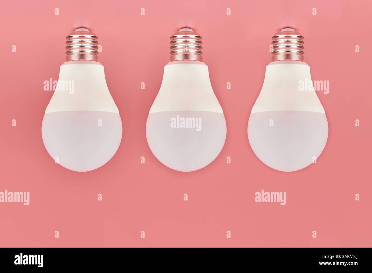 Three light bulbs, copy space. Energy saving minimal idea concept.Pink background. Stock Photo