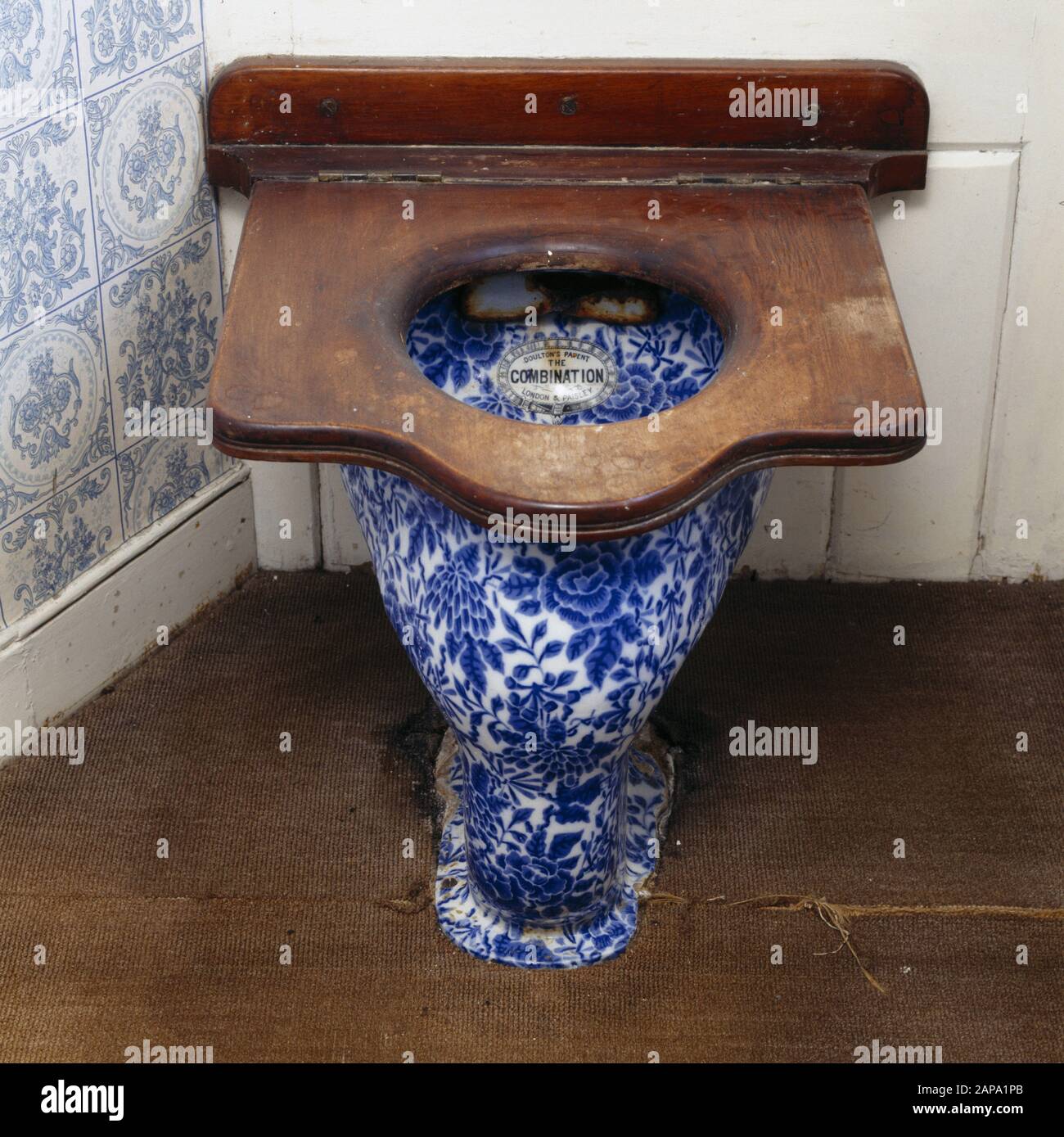 A blue and white floral patterned lavatory - The Combination by Doulton. A large wooden seat covers the bowl. Stock Photo