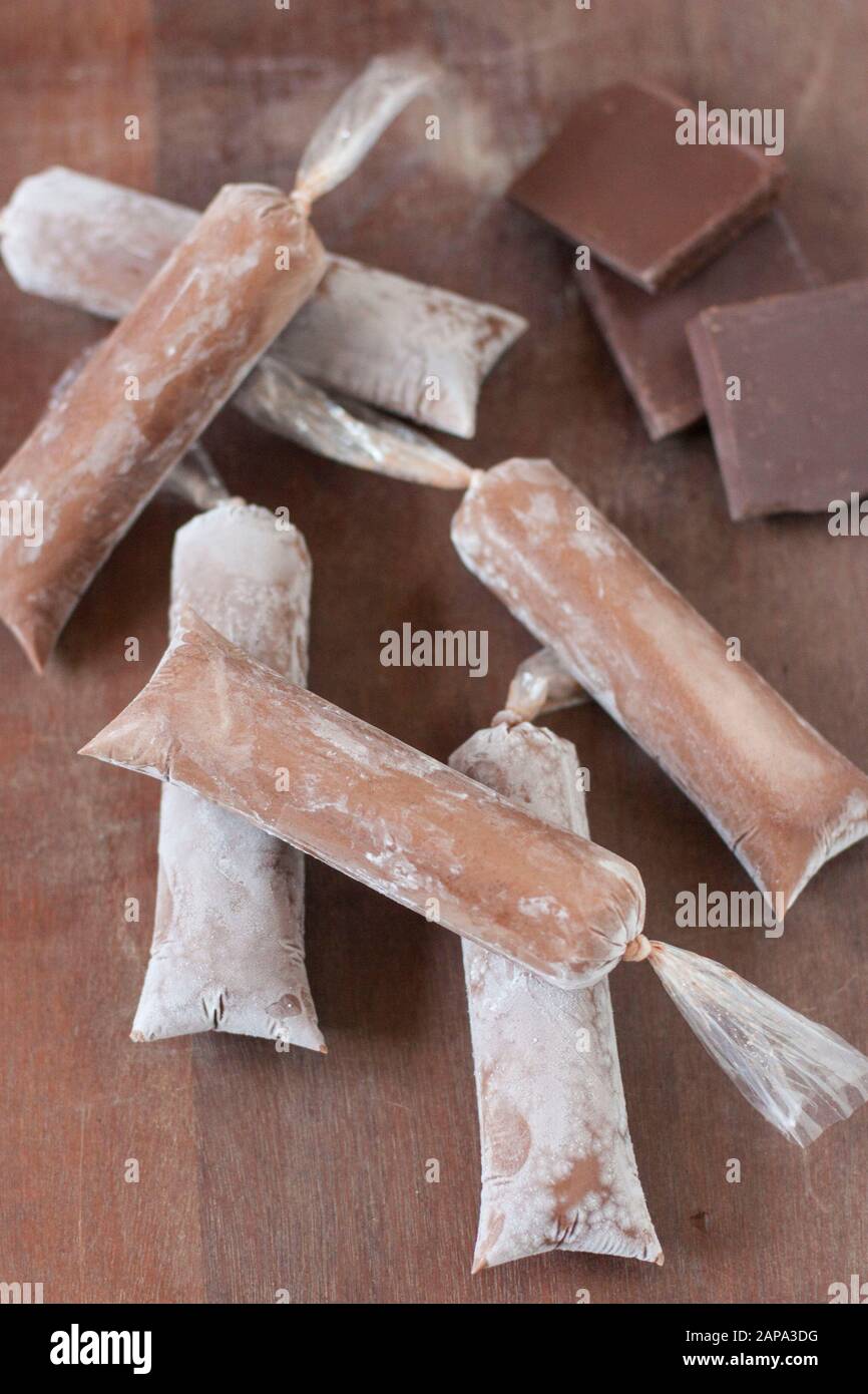 Six chocolate ice lollies over brown wood background with chocolate squares Stock Photo