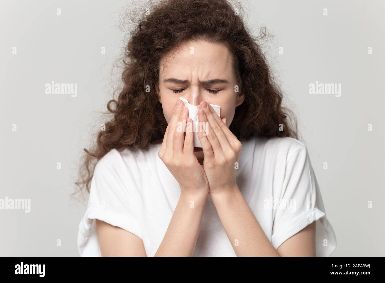 Close up portrait young unhealthy woman wiping runny nose Stock Photo
