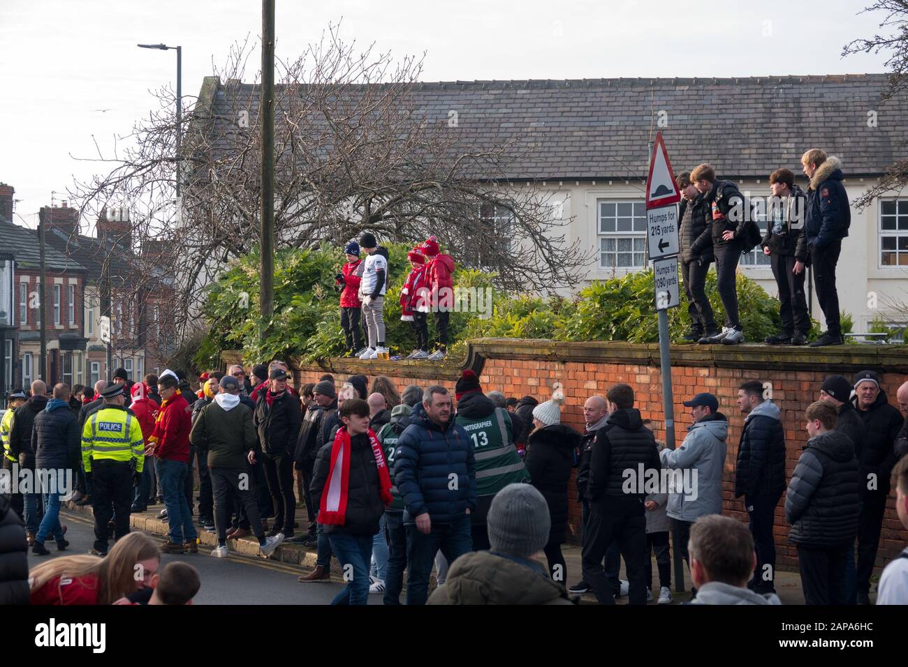 Small children wearing LFC colours standing on a wall waiting to greet the arrival Liverpool FC  team coach at Anfield Liverpool. Stock Photo