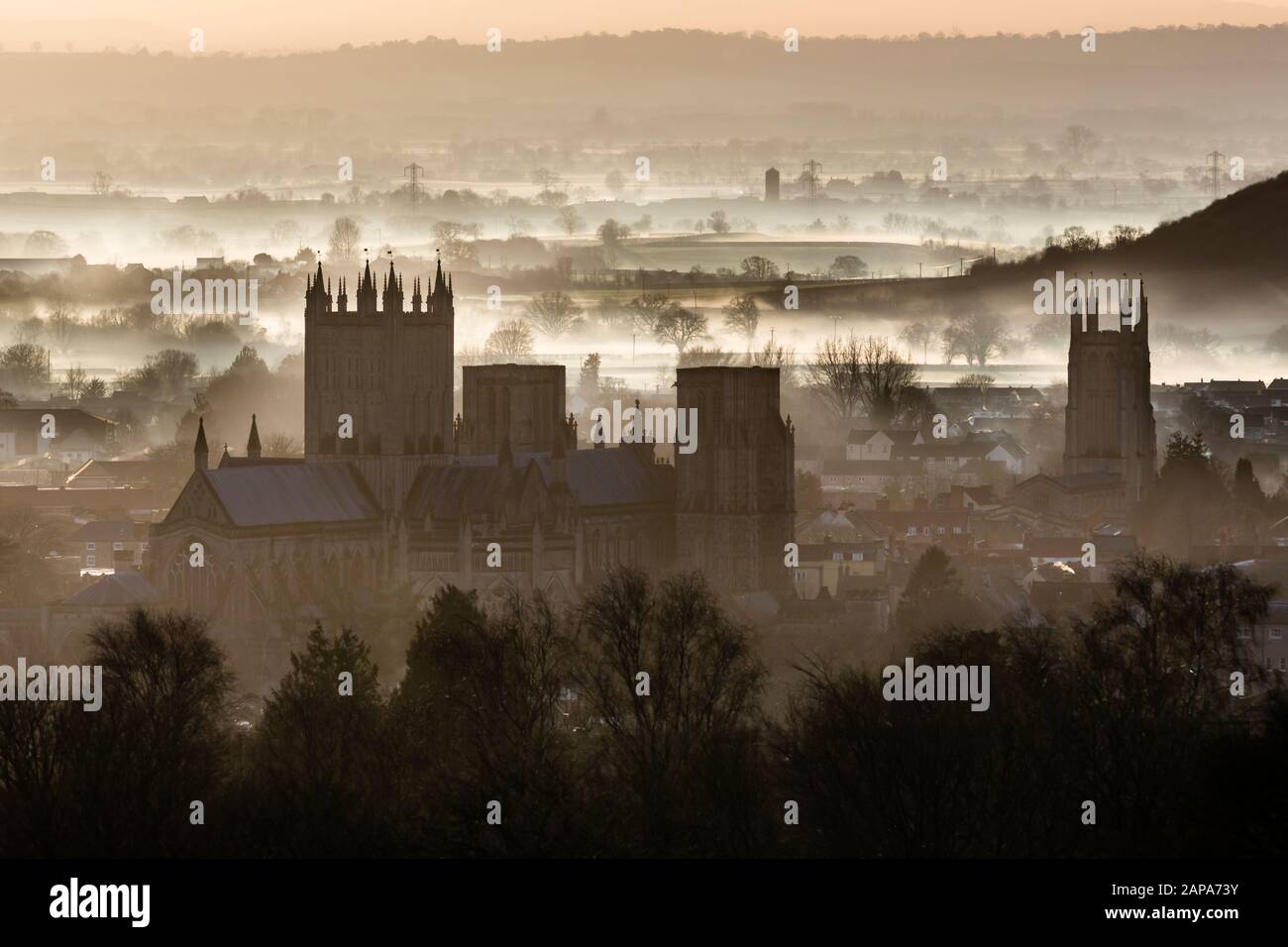 Wells Cathedral with St Cuthbert's - late winter afternoon looking out over fog on the Somerset Levels and Moors Stock Photo