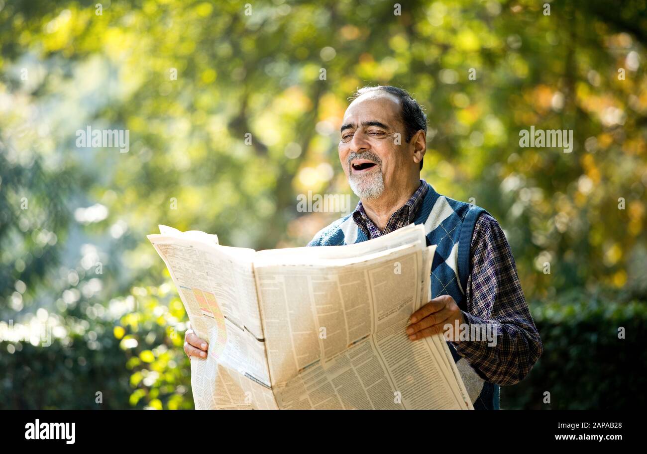 Senior man reading newspaper in the park Stock Photo