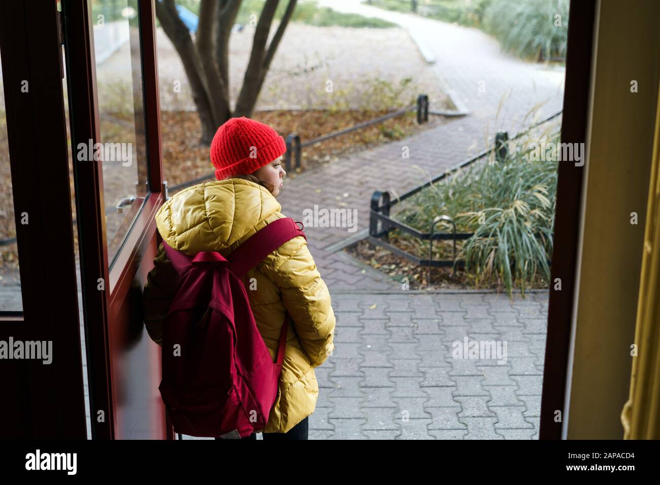 Girl 12 years old schoolgirl leaving the house with a backpack opening the door Stock Photo