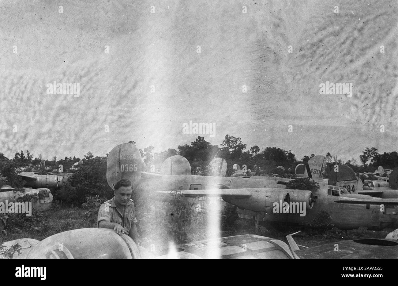 New Guinea series Description: American aircraft dump on the island of Biak. Dutch air force military between the wrecks of warplanes, Annotation: Boeing B-24 Liberator. On the tail the registration number 44-0365 Date: October 1948 Location: Biak, Indonesia, Dutch East Indies Stock Photo