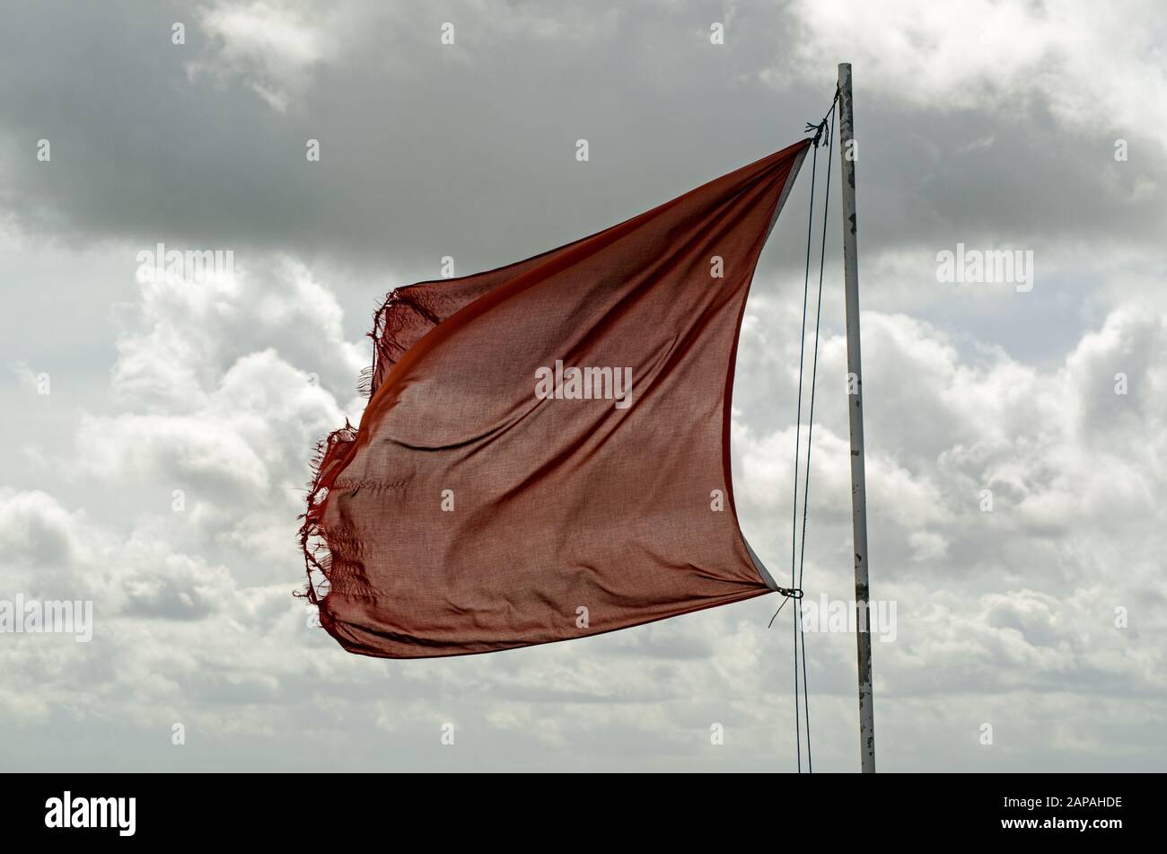 Slightly tatty red flag flying over Salisbury Plain in Wiltshire warning of army activity in the military controlled area. Stock Photo