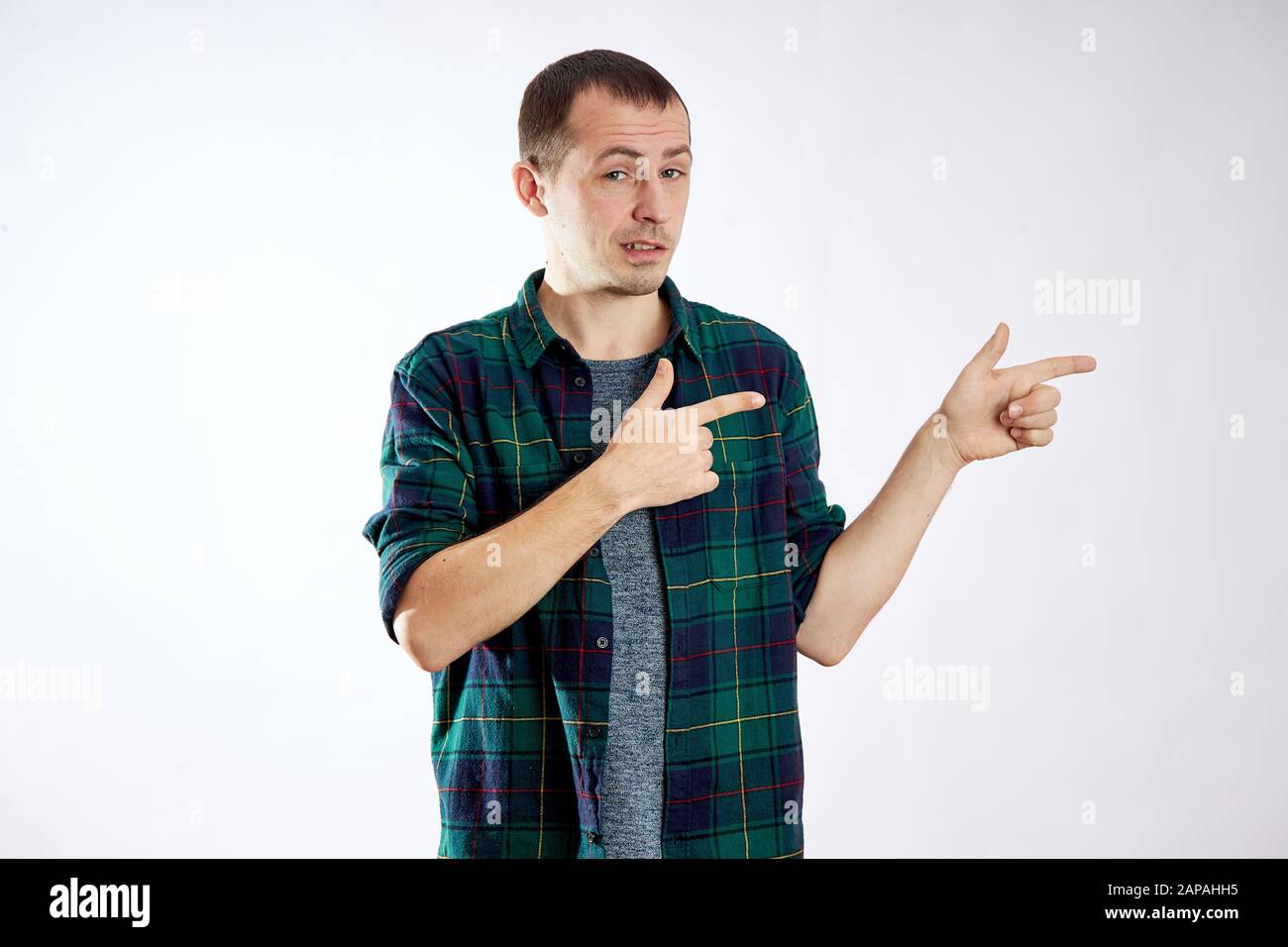 Man points his fingers to the left, makes gestures with his hands and smiles, advertising isolate Stock Photo