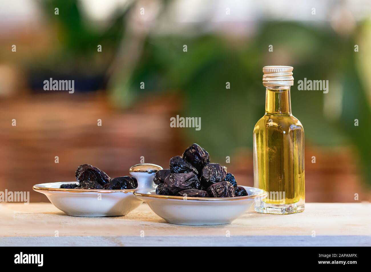 Wrinkled black greek olives and a liitle bottle with olive oil. Stock Photo