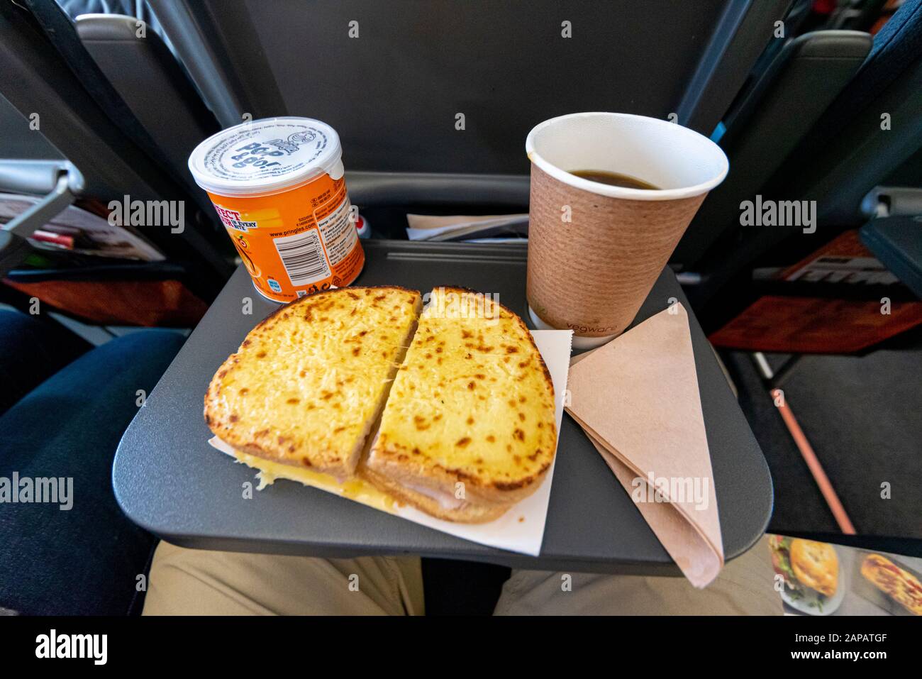 Meal deal food and drink on tray on an easyJet Airbus A320 NEO jet airliner plane. Ham and cheese toastie, Pringles crisps and coffee in flight meal Stock Photo