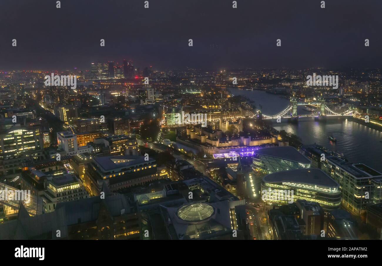 Night aerial view of Tower Bridge and City of London, England. Smog over city reduces view distance. City center at night lit with city lights Stock Photo