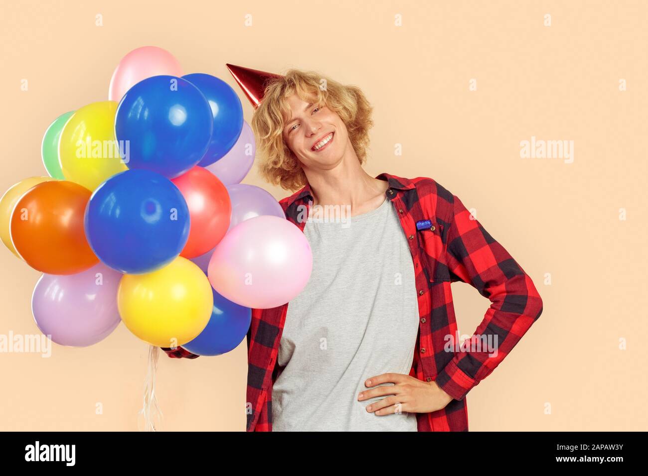 Young man holding helium balloons in hands Stock Photo