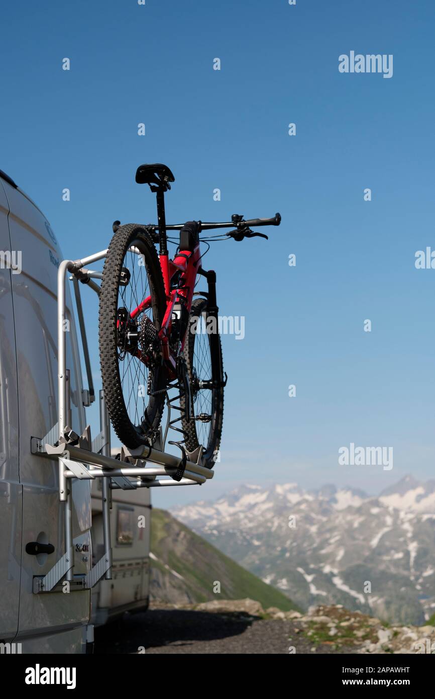 A camper van with a mountain bike bicycle rack in the Swiss Alps mountain top landscape of Realp, Uri, Switzerland EU - outdoor activity lifestyle Stock Photo