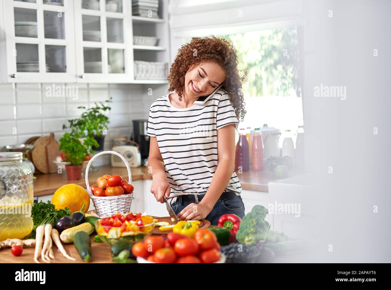 Woman making a call while cooking Stock Photo