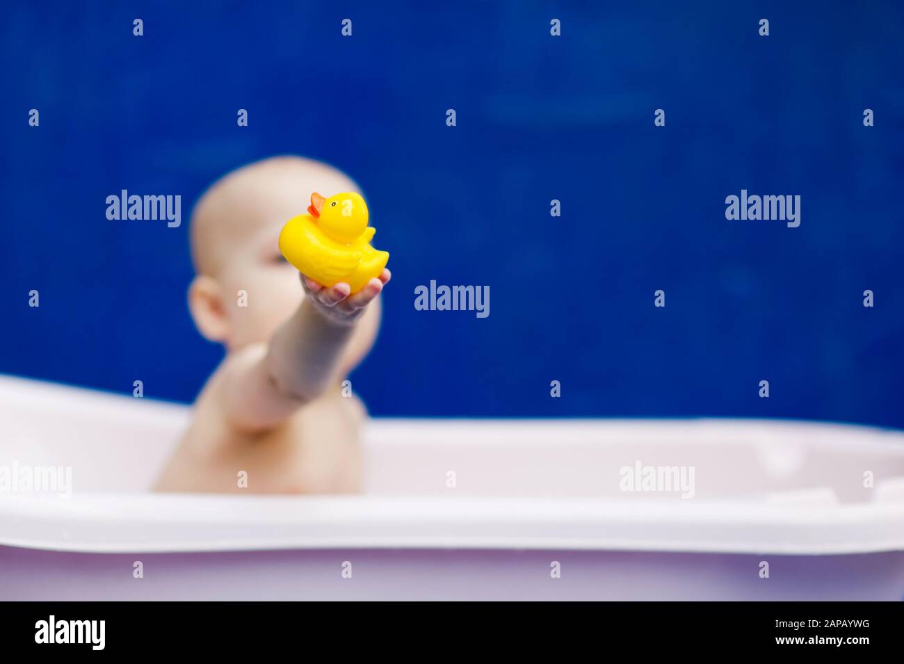 little girl sitting in a white bath with a rubber duck Stock Photo