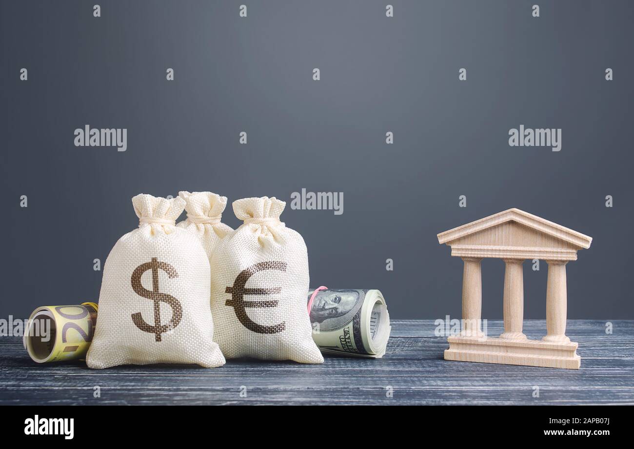 Money bags and a bank building. Saving money, deposit. National economy, investment and currency accumulation. Leasing and loans, registered capital. Stock Photo