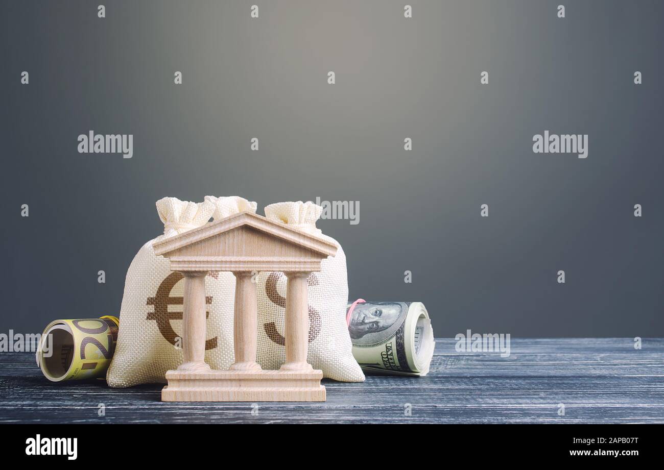 Money bags behind bank building. Leasing and loans, registered capital. Concealment of sources of funds origin and suspicious financial transactions. Stock Photo