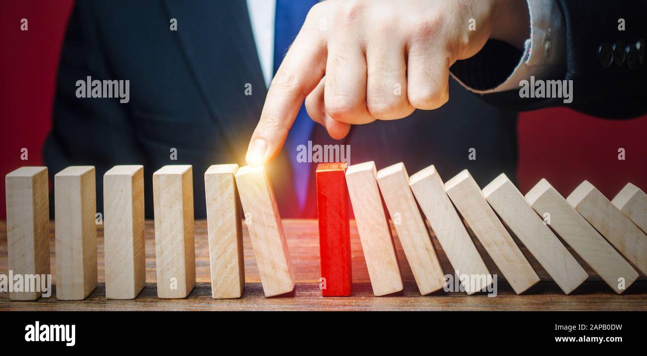 Businessman restarts the process of falling dominoes. Start work after stopping. Continuation of working, obstacle avoidance. maintainability. After t Stock Photo