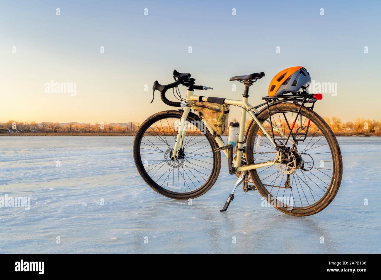 Winter biking, touring or commuting - bicycle on an icy lake. Helmet on racks, frame bag, kickstand. Riverbend Ponds Natural Area in Fort Collins, Col Stock Photo