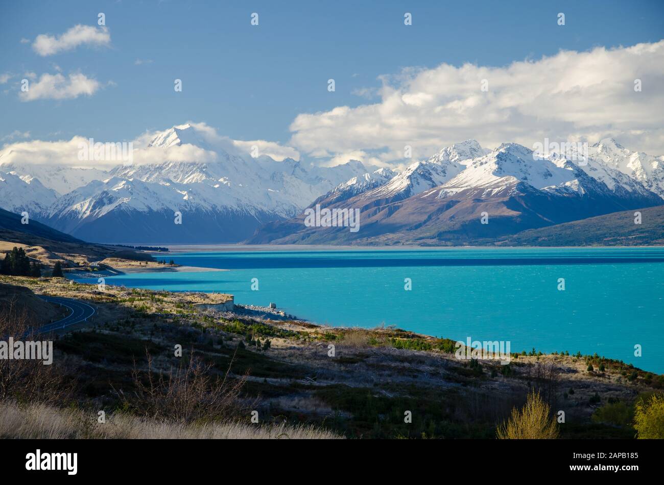 Snow covered Mount Cook with Lake Pukaki in the foreground and blue sky and white clouds, South Island, New Zealand Stock Photo