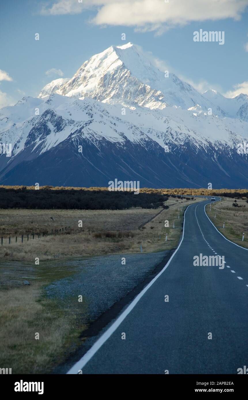 Snow covered Mount Cook with road in the foreground amd blue sky and white clouds, South Island, New Zealand Stock Photo