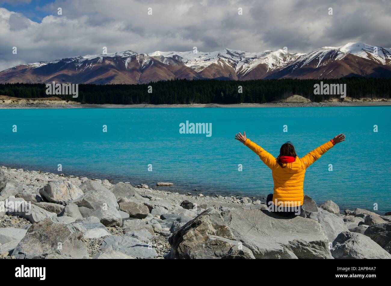 Lake Pukaki with orange girl person and snow covered mountains, South Island, New Zealand Stock Photo