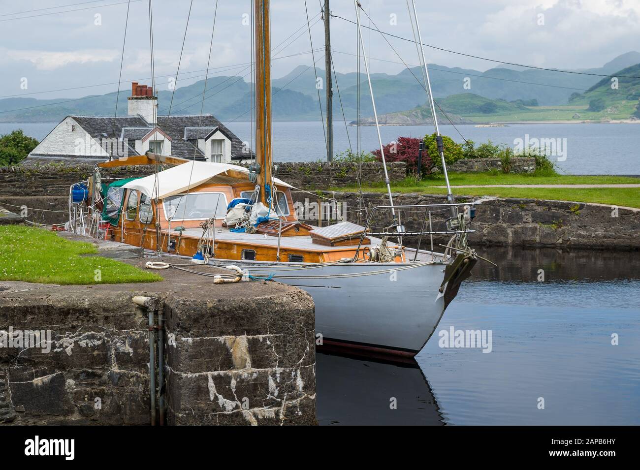 Sailing boat with white hull and old wooden deck and masts docked at Crinan, Scotland. Stock Photo