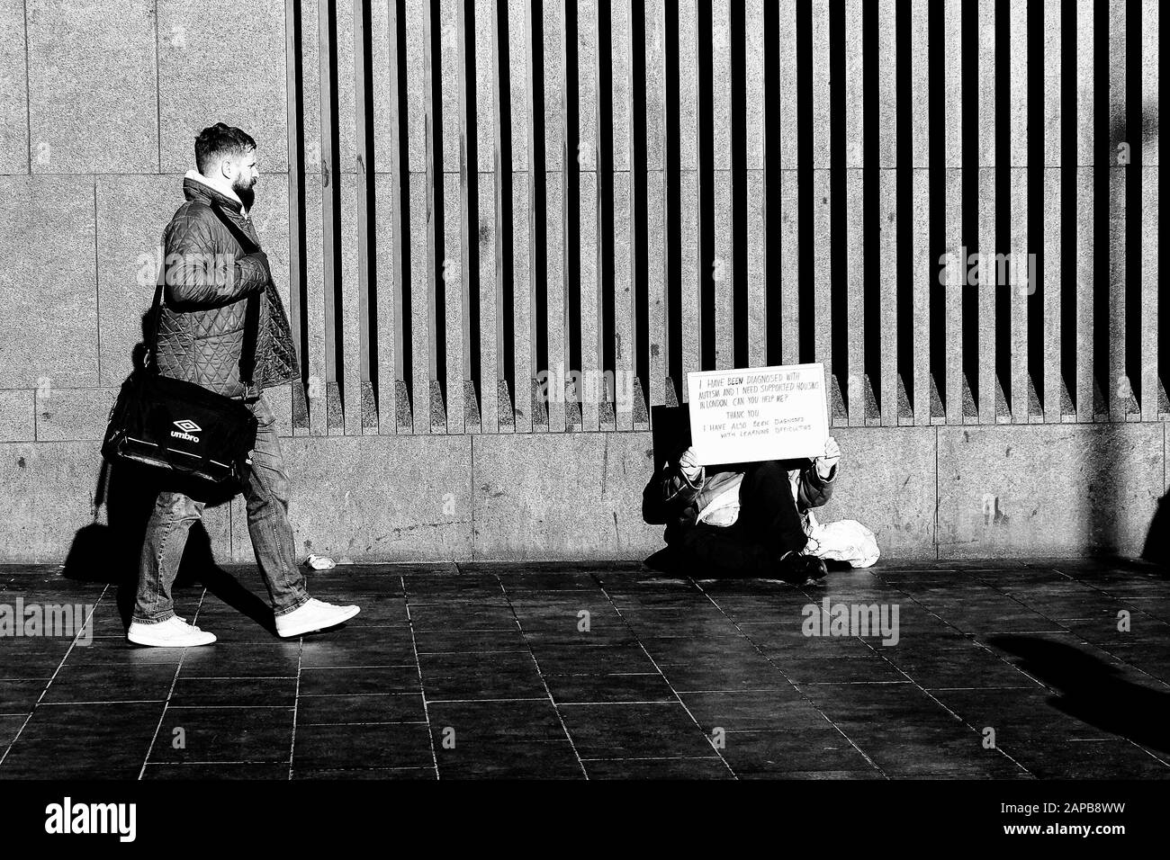 London 21st December 2020: Old Homeless man lays asleep with his personal belongings a younger man displays a sign asking for help, despite a multi-million pound refurbishment, Kings Cross Square, Underground train station is still attraction for homeless, with homelessness rising, stations have their own policy as to how and when rough sleepers are asked to leave, with over a 16000 people sleeping rough nightly in London. The government provides funding to keep a number of homeless shelters running. The winters months are the worst for rough sleepers with freezing conditions.  :Clifford Norto Stock Photo