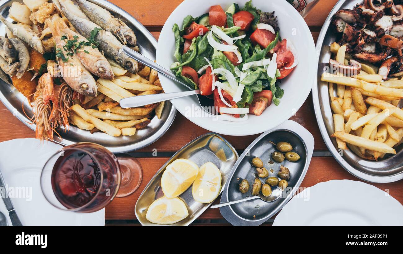 Flat lay of Cyprus fish and seafood meze with olives, lemon and Greek salad. Still life of mediterranean cuisine dishes. Stock Photo