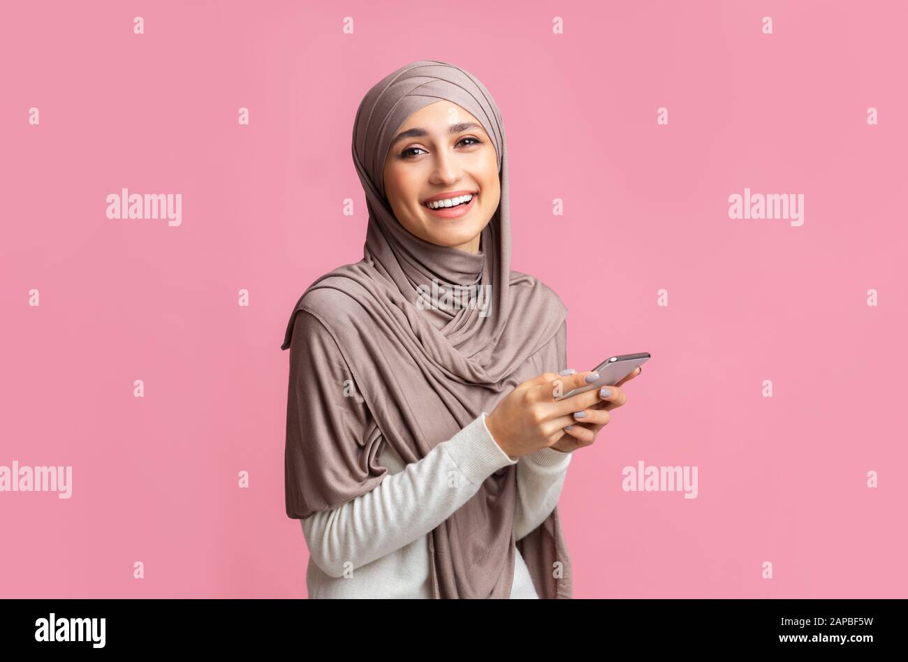 Portrait of smiling muslim woman in hijab using smartphone Stock Photo ...