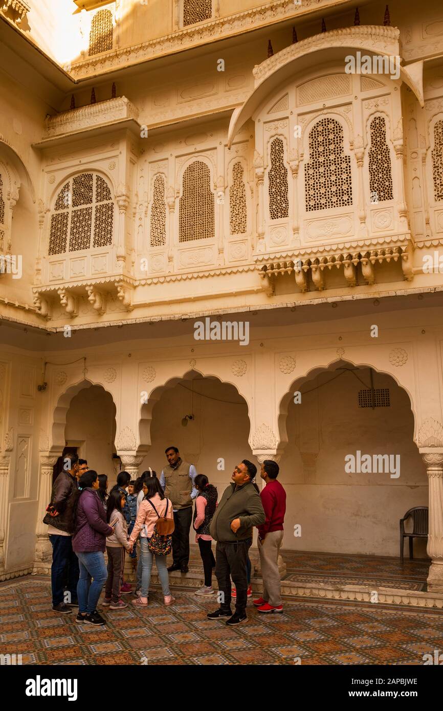 India, Rajasthan, Shekhawati, Bikaner, city centre, Junagarh Fort, group of Indian tourists in courtyard below finely carved Jarokha balcony with zenz Stock Photo