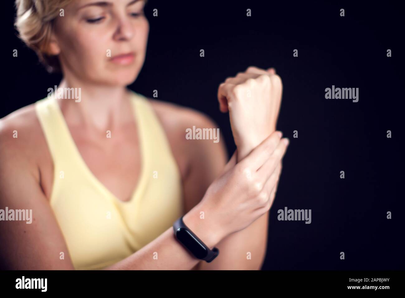 Woman with short blond hair feeling strong arm pain. Fitness and healthcare concept Stock Photo