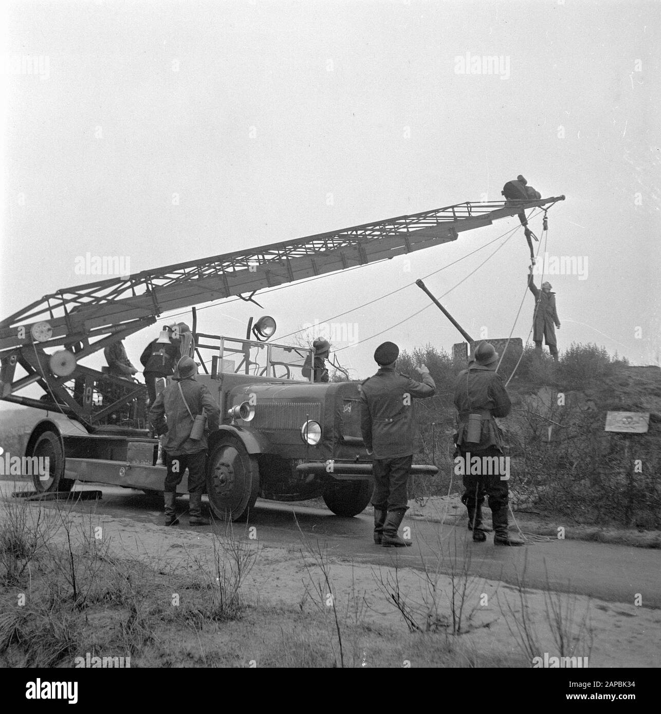 The Hague police and fire department rescue a boy from a former German bunker in a minefield. He was rescued with the help of the Magirus car ladder of the Hague Fire Department Date: 24 December 1945 Location: The Hague, Zuid-Holland Keywords: fire brigade, explosives, children, police, rescue personname: Magirus Stock Photo