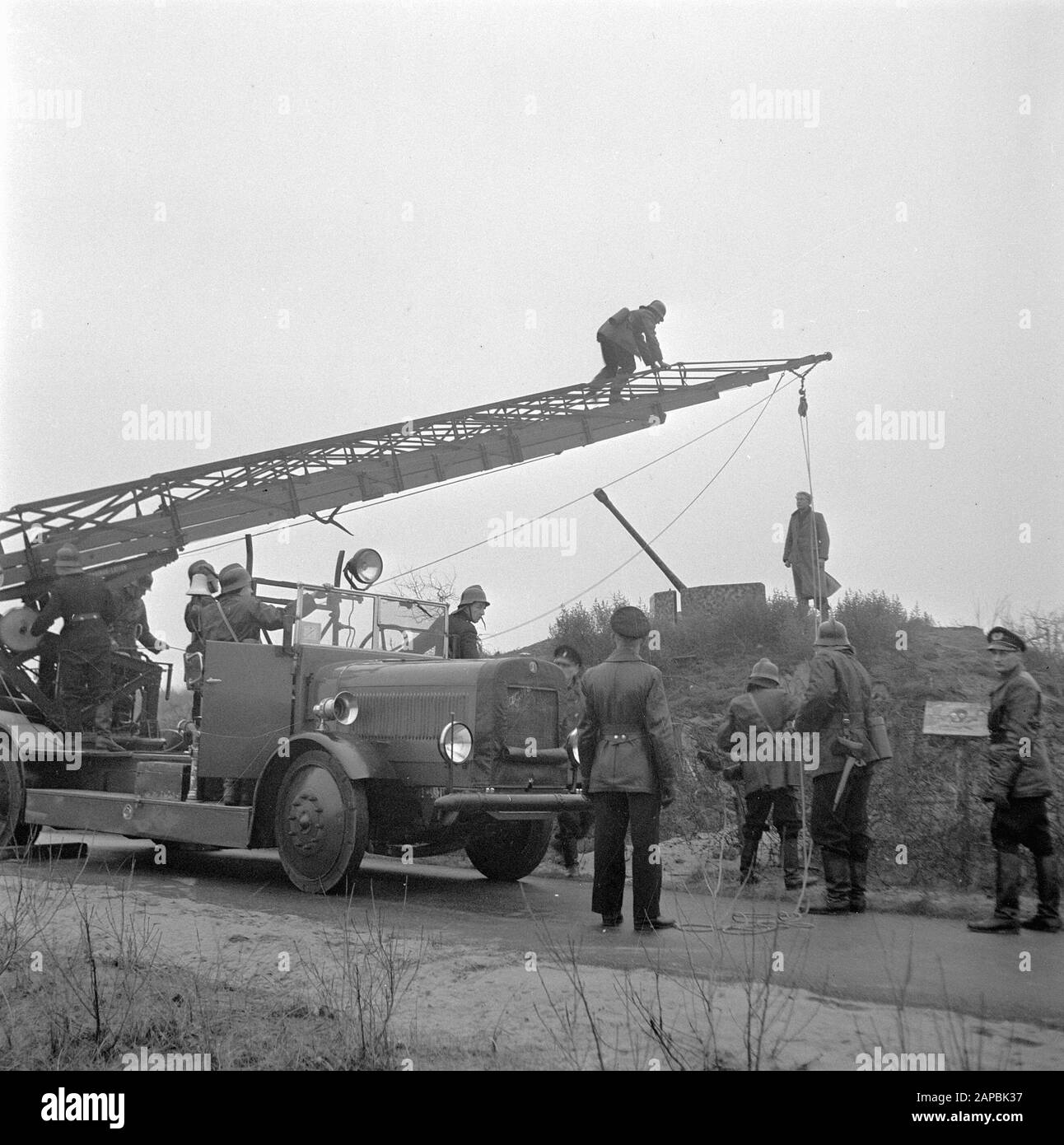 The Hague police and fire department rescue a boy from a former German bunker in a minefield. He was rescued with the help of the Magirus car ladder of the Hague Fire Department Date: 24 December 1945 Location: The Hague, Zuid-Holland Keywords: fire brigade, explosives, children, police, rescue personname: Magirus Stock Photo