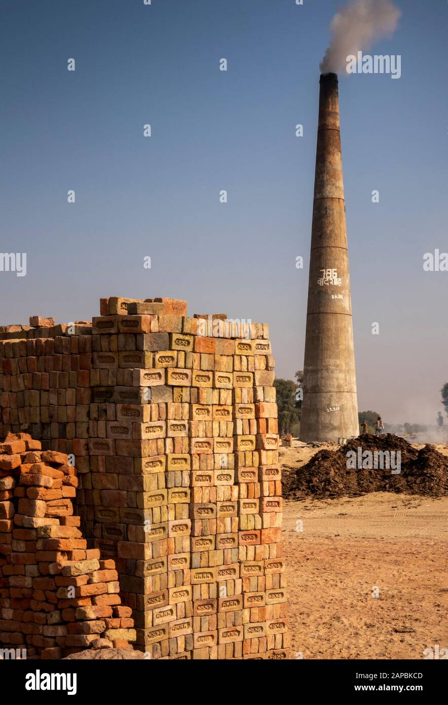India, Rajasthan, Shekhawati, Bikaner, Gajner, Industry, brickworks, smoking chimney during firing and pile of bricks Stock Photo