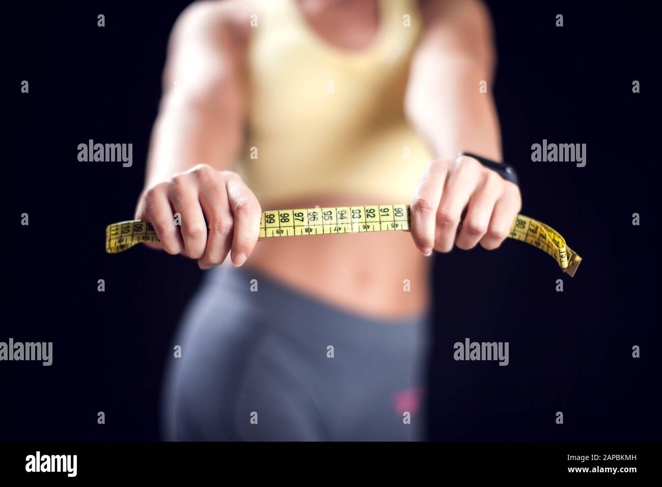 Woman with short blond hair in sport clothes holding measurement tape. Fitness, diet and healthcare concept Stock Photo