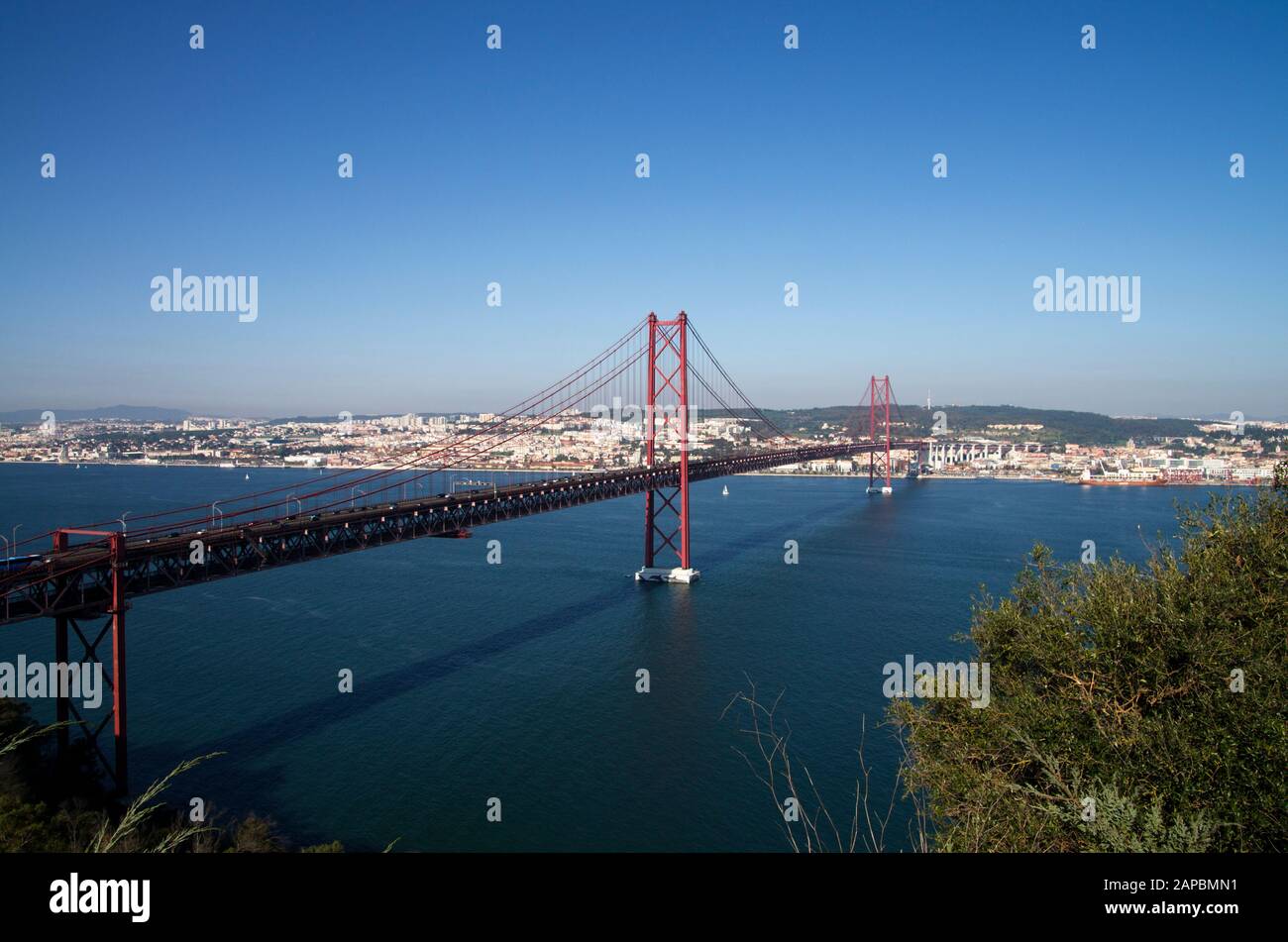 Lisbon 25th of April suspension bridge connecting to Almada over the Tagus River. View from above at the south bank with part of Lisbon city as backgr Stock Photo
