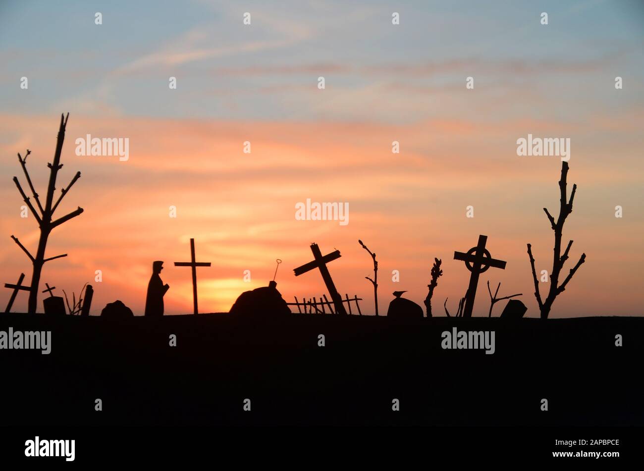Silhouette of decayed graveyard with tilted crosses and tombstones in sunset light. Stock Photo