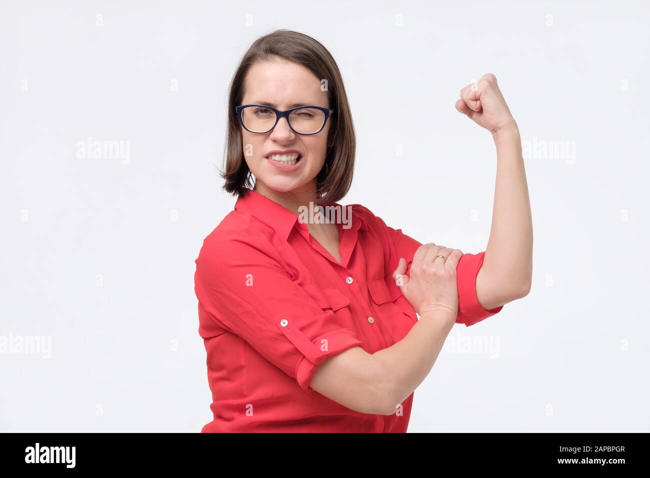 Young caucasian woman flexing her biceps showing her strength and